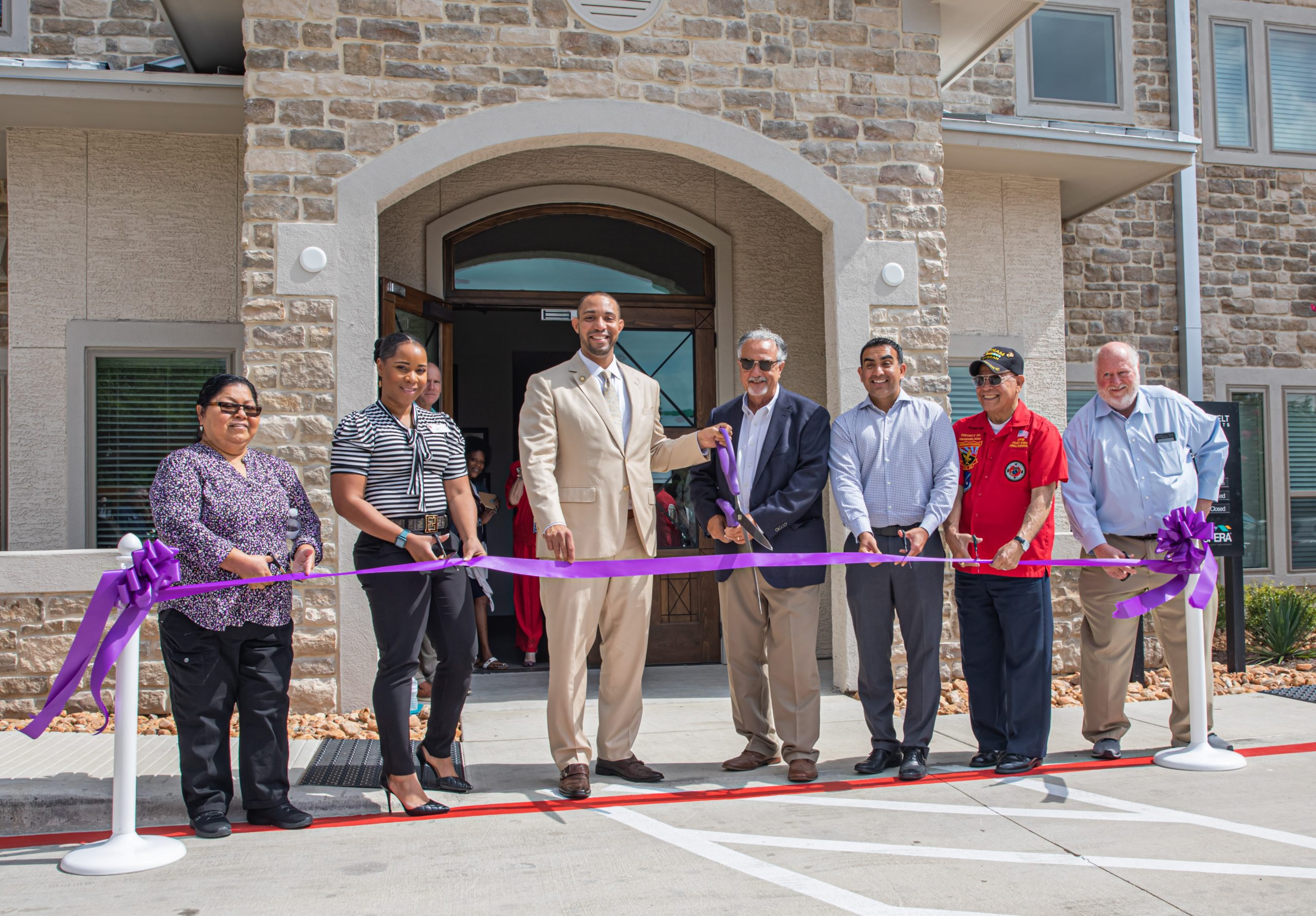 Dignitaries with scissors standing to cut ribbon