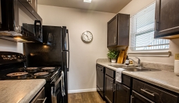 ktichen galley with counters, sink, electric oven, microwave, refrigerator, and window