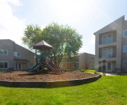 Outside playscape with two-story and three-story apartment building in background