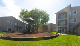 Outside playscape with two-story and three-story apartment building in background